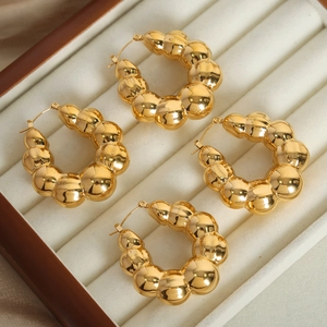 Golden U-shaped earrings with unique bubbly geometric texture on velvet jewelry box