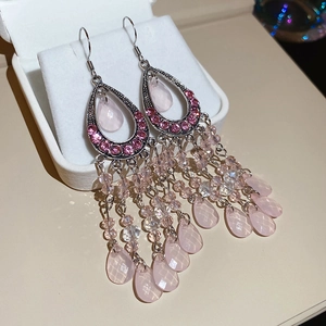 Detail of pink crystal tassel earrings with teardrop gems and bohemian beaded fringe