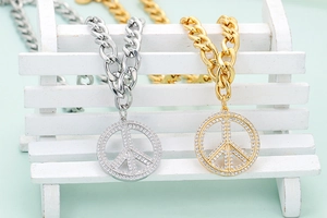 Close-up of gold and silver peace sign pendants with micro-paved cubic zirconia