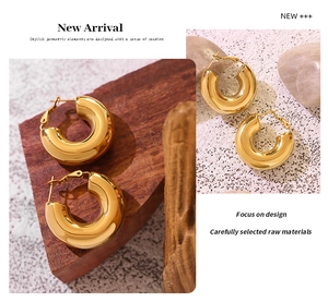 Polished thick gold geometric U-shaped hoop earrings displayed on premium natural textures