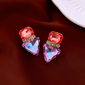 Detail of vintage wing earrings with red rectangular and purple gradient triangle gems