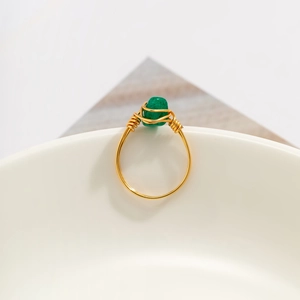 Detail of handcrafted gold wire wrapped ring featuring a natural green stone accent