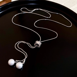 Gros plan sur collier chaîne serpent argenté avec deux perles blanches et zircons
