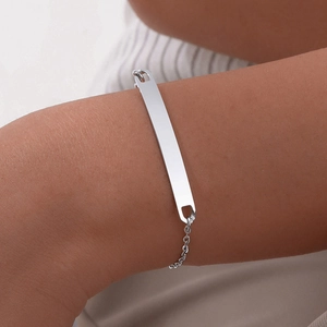 Detailed view of a silver minimalist curved bar bracelet worn on a woman's wrist