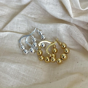 Macro detail of S925 sterling silver beaded hoop earrings in gold and silver finish