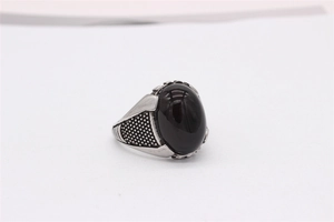 Gros plan détaillé sur la bague ovale à pierre noire avec des motifs vintage gravés