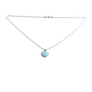 Macro detail of sky blue heart stone pendant and silver twist chain on white background