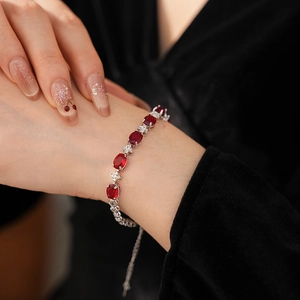 Detailed view of silver bracelet featuring oval red stones and floral zircon links
