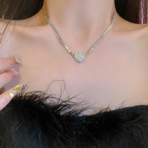 Close-up of double-layered silver heart necklace with pavé zircons on elegant model