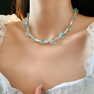 Dettaglio di collana di perle blu chiaro e grani d'argento su una modella