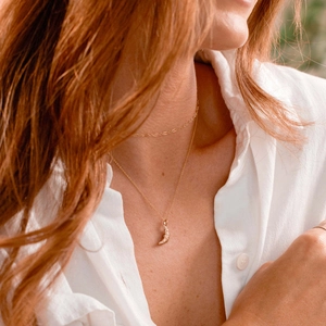 Close-up of golden moon pendant necklace with unique texture on a model neckline