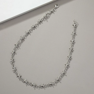 Punk silver barbed wire knot necklace with metallic luster on textured background