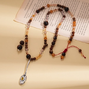Ethnic style beaded long necklace featuring a silver spoon pendant with a yellow gemstone