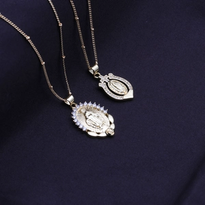 Gold plated heart Virgin Mary necklaces with sparkling crystals on dark blue fabric