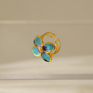 Macro detail of gold plated stainless steel flower ring with blue and purple enamel