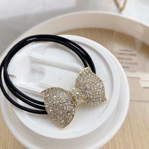 Détail d'un élastique à cheveux noir avec un nœud papillon serti de strass brillants