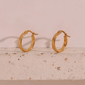 Macro view of 20mm gold-plated stainless steel hoop earrings with diagonal textured stripes