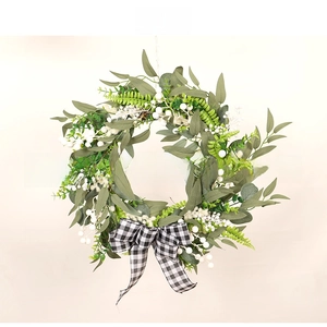 Macro detail of artificial green foliage wreath with white berries and checkered bow