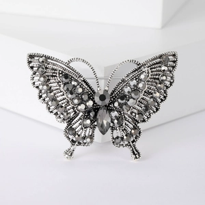 Detailed view of vintage silver butterfly brooch with dark grey rhinestones on white display