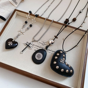 Detailed view of assorted gothic cross and leather heart pendants on a wooden jewelry tray