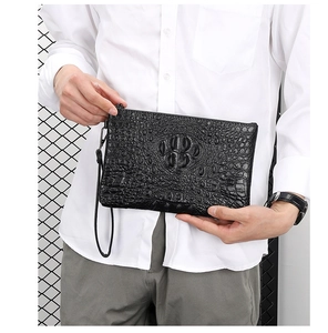 Detailed view of black crocodile pattern leather texture on a men's wristlet clutch bag