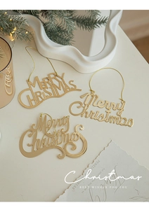 Close-up of three shiny gold Merry Christmas hanging ornaments with golden strings