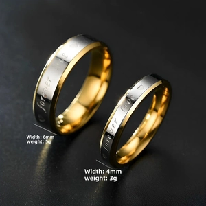 Macro shot of silver and gold couple rings engraved with Forever Love on black leather