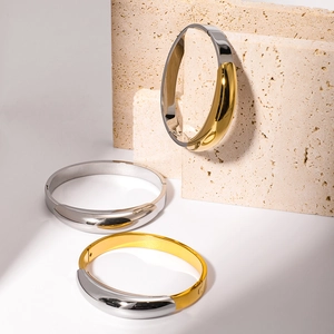 Minimalist 18k gold plated stainless steel two-tone bangle set on stone pedestal