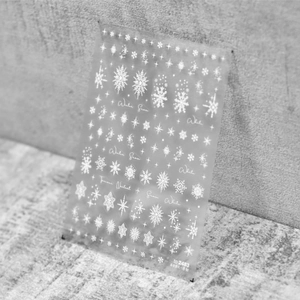 Détails d'autocollants pour ongles fins à flocons blancs sur fond gris texturé