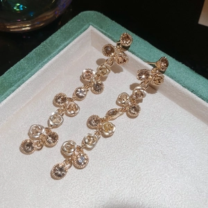 Detail view of sparkling floral tassel earrings with zircon stones on green velvet box
