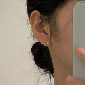 Close-up of minimalist floral stud earrings with white enamel and silver outlines