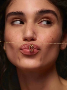 Creative close-up of colorful zircon letter S pendant necklace on model lips