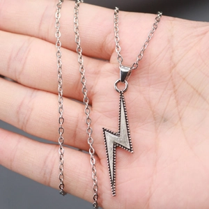 Luminous lightning bolt pendant necklace in stainless steel held in a palm