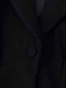 Detailed macro view of the shawl collar and fabric covered button on a black wool coat