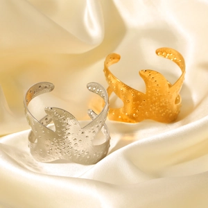 Detailed view of gold and silver hammered starfish bangles on soft beige satin fabric