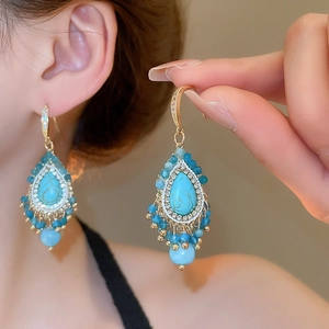 Close-up of bohemian turquoise drop earrings with fringe tassels and gold plating