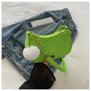 Detalle de bolso acolchado verde neón con pompón blanco y cadena dorada en denim