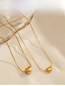 Gros plan détaillé de deux colliers avec pendentif cœur plaqué or 18 carats sur satin