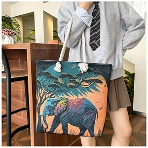 Detail of embroidered elephant tote bag featuring sunset savanna scenery and cotton rope handle