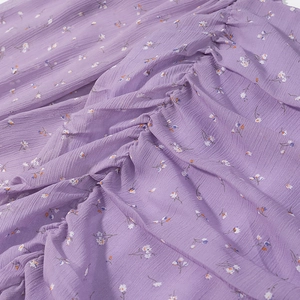 Dettaglio del tessuto chiffon floreale viola con trama increspata e piccoli fiori colorati