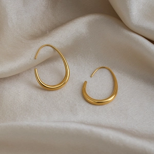 Detail of 18K gold-plated U-shaped drop earrings on elegant beige silk fabric