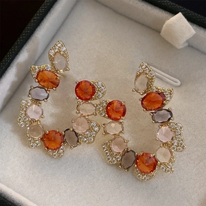 Detailed macro shot of vintage C-shape earrings with colorful zircon and gold plating