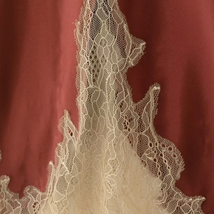 Elegant brick red satin skirt featuring delicate cream lace trim detailing