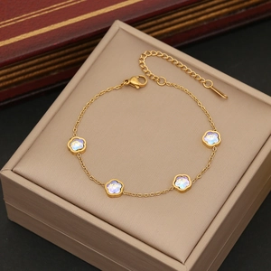 Golden delicate bracelet with four iridescent five-petal flower charms on display box