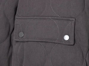 Macro shot of dark grey quilted jacket showing textured fabric and dual metal snap pocket