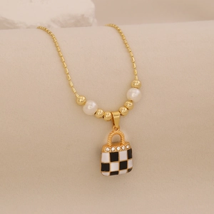 Detail of gold necklace featuring pearl accents and a black and white plaid bag pendant