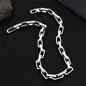 Detail shot of silver hip-hop chain with embossed textured rectangular links on dark background