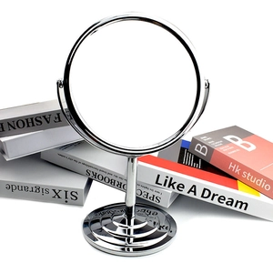 Detail of a round double-sided makeup mirror with a stable base and decorative books