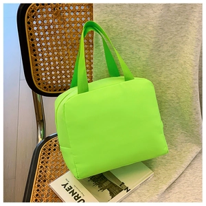 Neon green insulated lunch bag with top handles placed on a rustic wicker chair detail