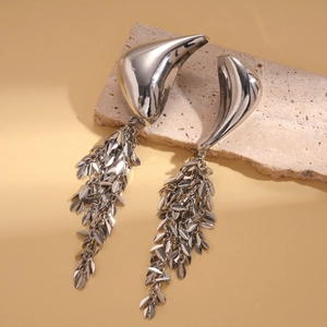 Detail of silver metallic fringe earrings with irregular curved surface on a stone base
